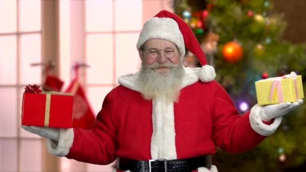 Santa Claus in eyeglasses holding Christmas gifts. — Stock Video
