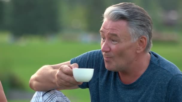 Szczęśliwy, uśmiechnięty mężczyzna na zewnątrz picia herbaty. — Wideo stockowe