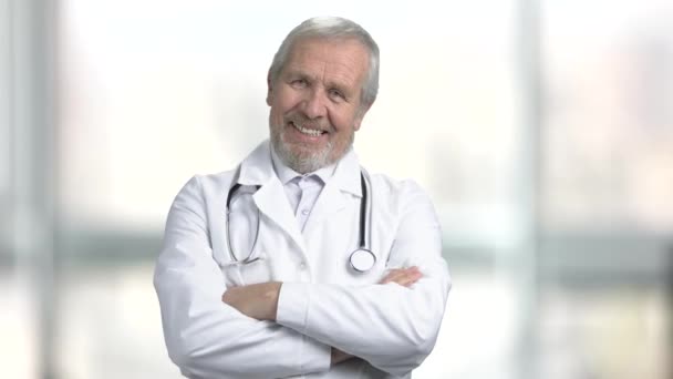 Starszym lekarzem uśmiechający się na niewyraźne tło. — Wideo stockowe