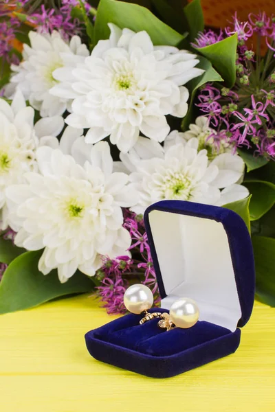 Pearl earrings in the gift box with flowers.