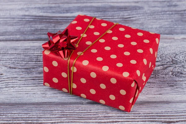 Red dotted gift box on wooden background.