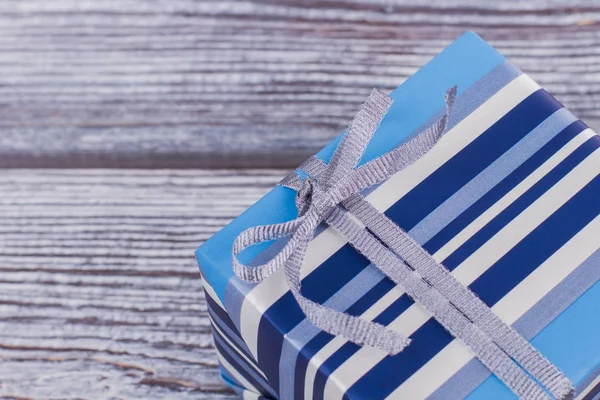 Blauw gestreepte geschenkdoos met grijze lint. — Stockfoto