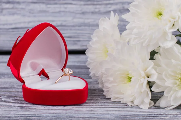 Engagement ring in box and white chrysanthemums.