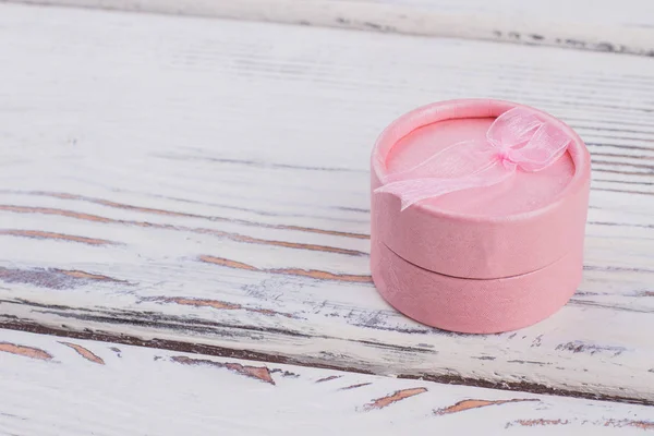 Round jewelry gift box on wooden background.