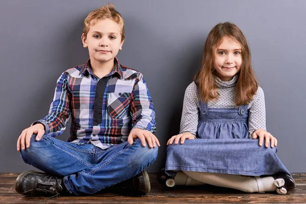 Dos niños sentados con las piernas cruzadas . — Foto de Stock