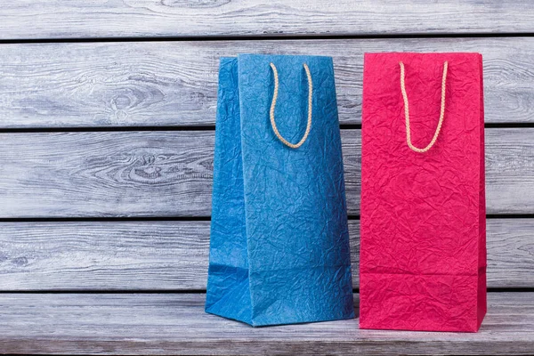 Bolsas de compras azules y rosas sobre fondo de madera . — Foto de Stock