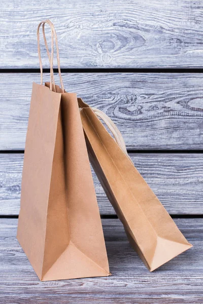 Kraft paper shopping bags on wooden background.