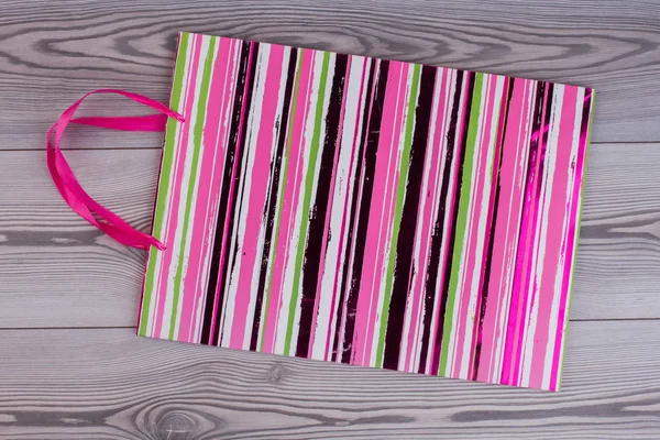 Ροζ ριγέ δώρο τσάντα σε φόντο ξύλινη. — Φωτογραφία Αρχείου