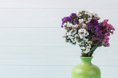 Yeşil bir seramik vazoda farklı statice limonium çiçekler.