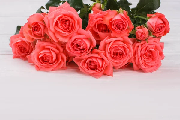 Buquê de rosas vermelhas florescendo na mesa de madeira branca . — Fotografia de Stock