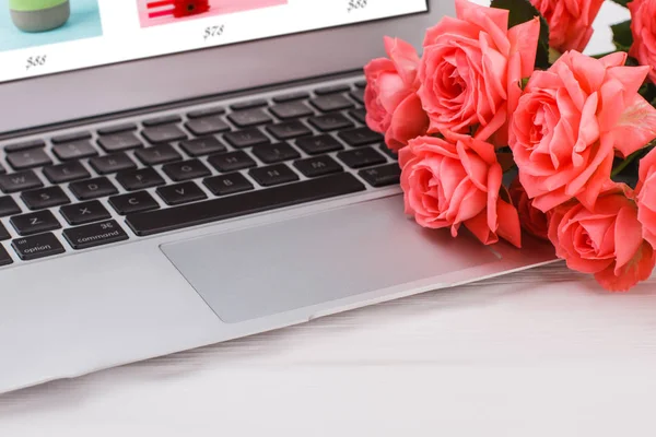 Laptop pc and roses flowers, close up.