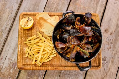 Kabuklu midye tencerede limon ve patates kızartması ile.