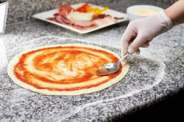 Eli kaşık sos pizza kabuk üzerinde bulaşması ile yakın.