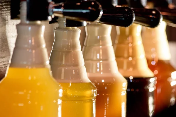 Row of bottles with beer and foam.