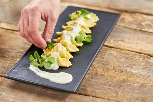 Kocken hand lägga gröna till ravioli skålen. — Stockfoto