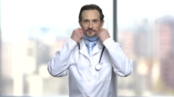 Knappe dokter legt op medische masker. — Stockvideo