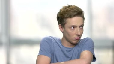 Üzgün portresi genç adam rahatsız. Arka plan bulanık çapraz silah memnun beyaz çocuk. Memnun adam dil gösterilen.