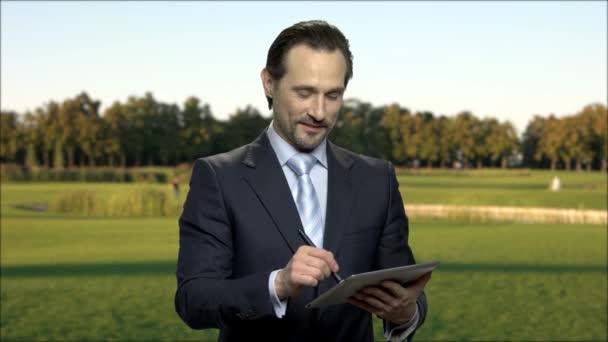 屋外デジタル タブレットを使用して魅力的なビジネスマン. — ストック動画