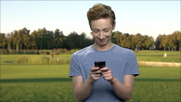 Adolescente niño usando teléfono inteligente al aire libre . — Vídeo de stock