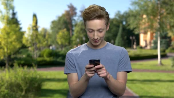 Adolescente niño usando el teléfono móvil al aire libre . — Vídeo de stock