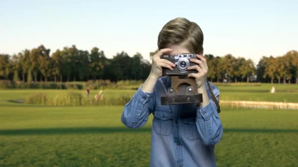 ビンテージ カメラを持った少年は、屋外の写真. — ストック動画