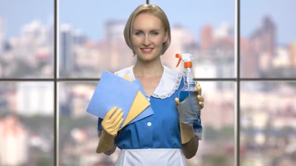 Sorrindo empregada doméstica segurando trapos e spray de limpeza . — Vídeo de Stock