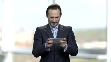 Neşeli işadamı onun smartphone oyun oynama.