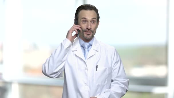 Возбужденный взрослый доктор разговаривает по телефону . — стоковое видео