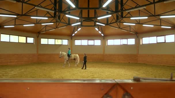 Jong meisje paardrijden paard binnenshuis. — Stockvideo