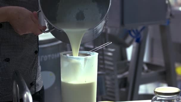 Рабочий наливает молоко в контейнер для превращения . — стоковое видео