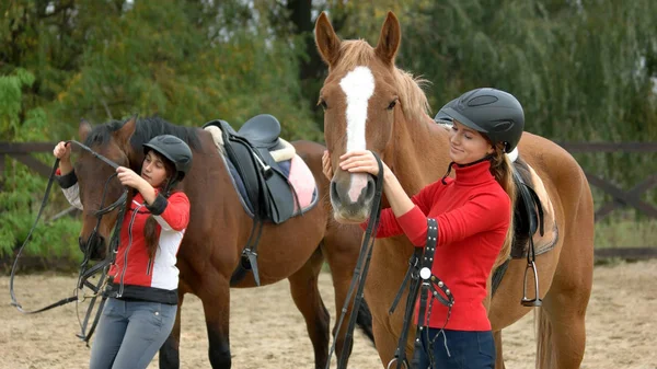 Mladé ženy, příprava koně pro jízdu. — Stock fotografie
