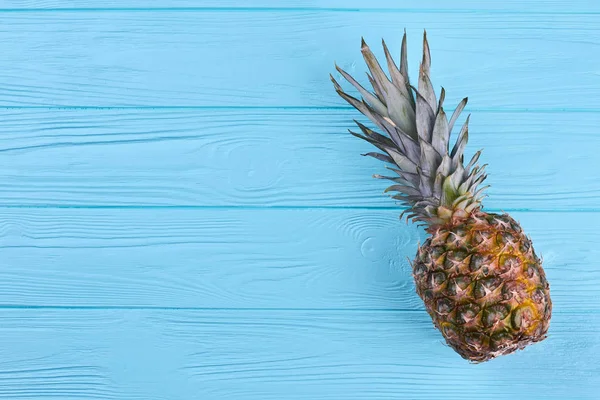 Pineapple on blue wooden background, top view. — Stock Photo, Image