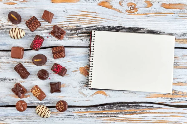 Grupo de doces de chocolate e caderno de papel . — Fotografia de Stock