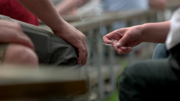 Ženská ruka s hořící cigaretou ve veřejném prostoru. — Stock video