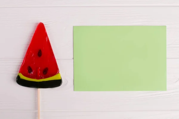 Lollipop watermeloen en blanco papier kaart. — Stockfoto