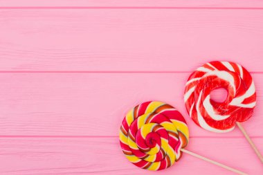 Pembe bir arka plan üzerinde renkli lolipop.