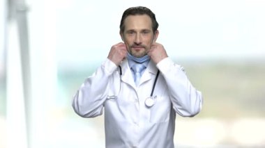 Doktor mavi tıbbi maske koyarak.
