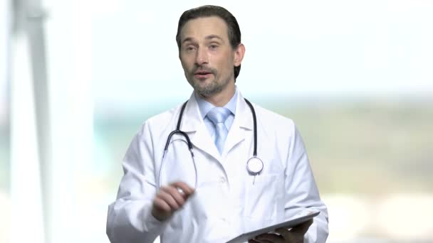 Médico sorridente a falar enquanto segura no comprimido. — Vídeo de Stock
