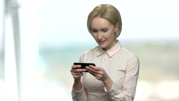 Bürofrau spielt Online-Spiel auf ihrem Handy. — Stockvideo
