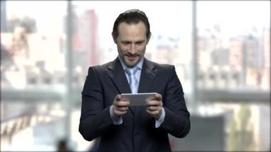 Telefonda çekici olgun işadamı oyun oynuyor.
