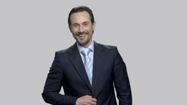 Gri arka planda olgun işadamı gülüyor.