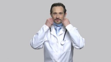Emin erkek doktor koruyucu maske koyar.