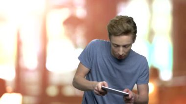 Konsantre genç çocuk telefonda oyun oynuyor.