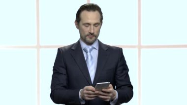 Akıllı telefon kullanarak olgun sakallı işadamı portresi.