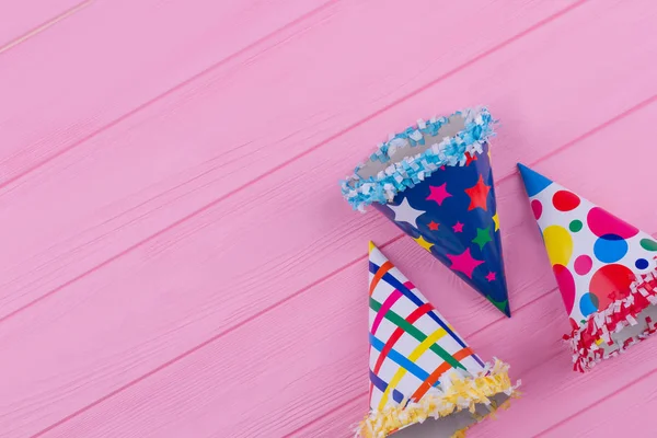 Sombreros de fiesta de papel sobre fondo de madera rosa . — Foto de Stock