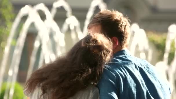 Young couple hugging at fountain, back view. — Stock Video