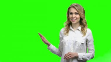 Genç ve çekici bir kadın yeşil ekranda bir şey sunuyor..