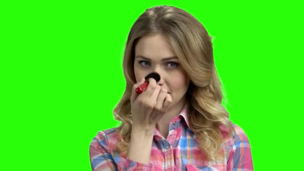 Charming girl puts on makeup on the green screen. — Stock Video