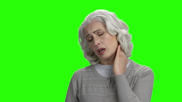 Starší šedovlasá žena trpí bolestí krku.
