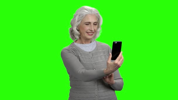 Old woman taking selfie on green screen. — Stock Video